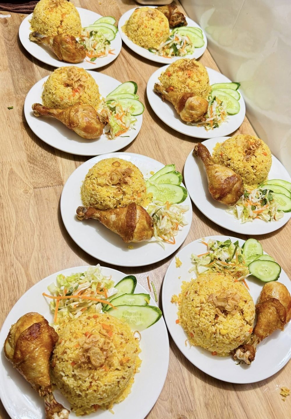 Several plates of turmeric-yellow rice with fried chicken legs and a salad garnish, Vietnam