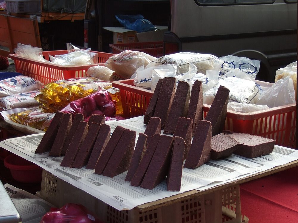 Dark purple-brown blocks of belacan, fermented shrimp paste, stacked for sale in a Malaysian market