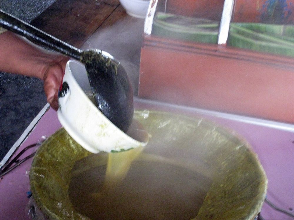 A street vendor in Bogor ladling yellow coconut broth from a large pot into a bowl