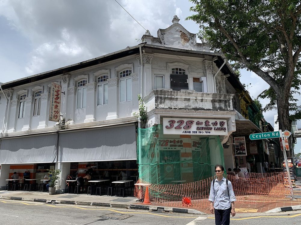 A white two-storey corner shophouse on East Coast Road, Singapore, with the 328 Katong Laksa signboard over the shopfront